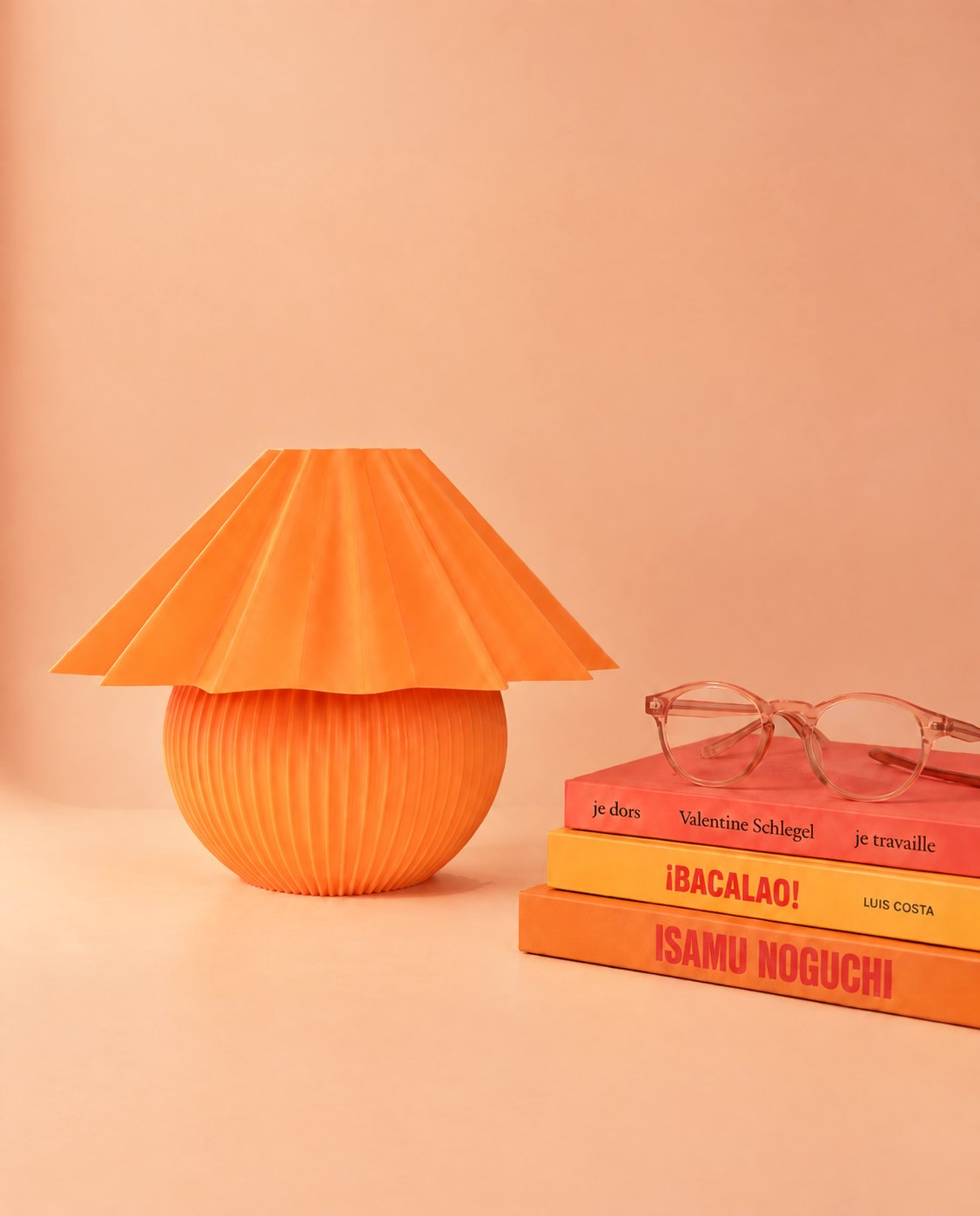 Penélope naranja junto a una pila de libros de diseño con unas gafas encima