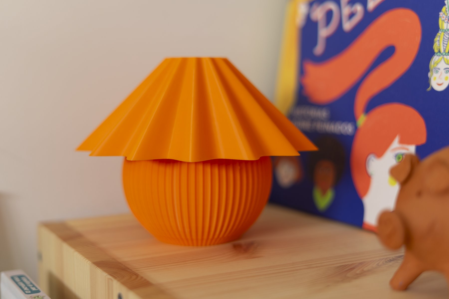 Penélope naranja en una estantería de madera, junto a un libro ilustrado