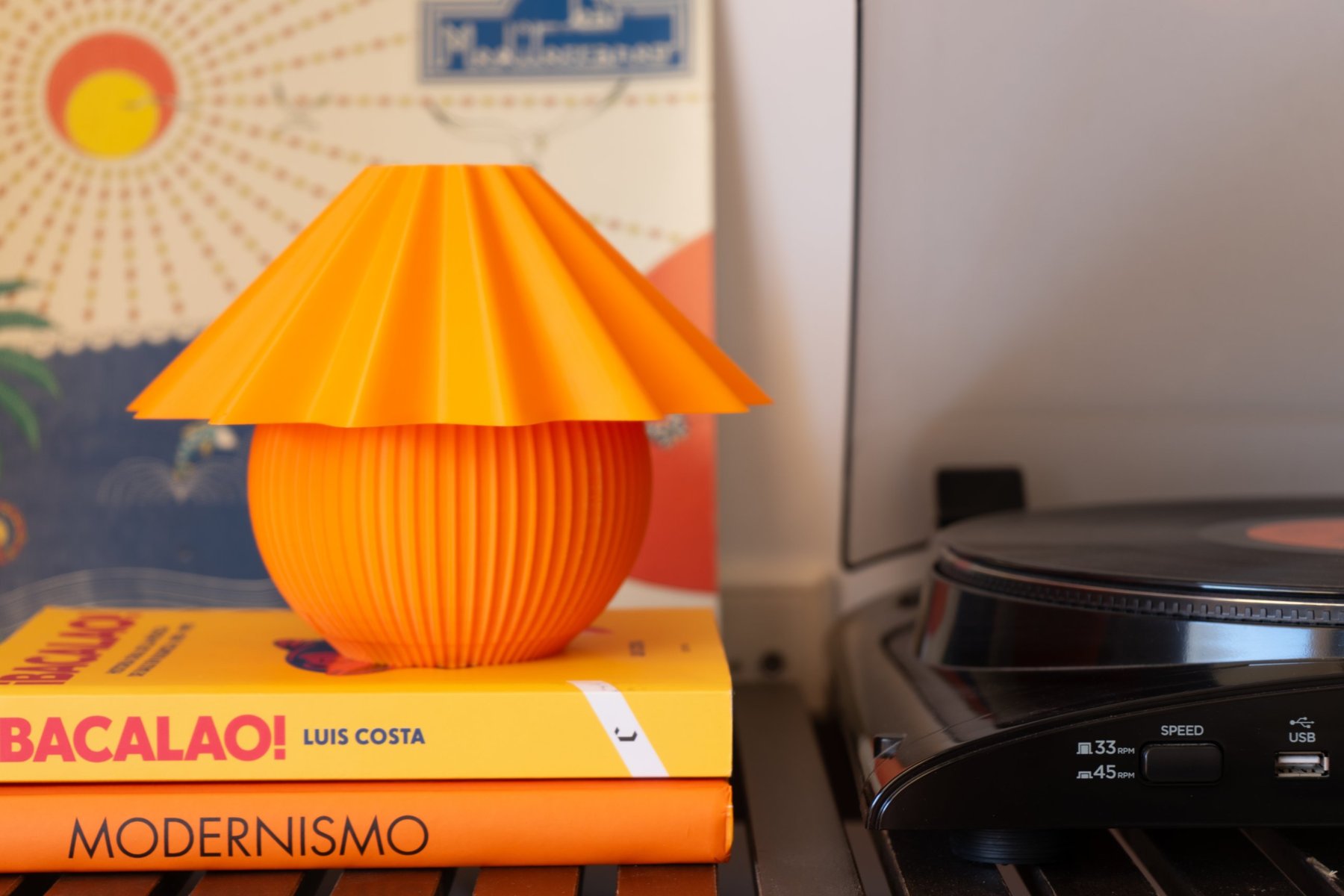 Penélope naranja sobre dos libros, junto a un tocadiscos